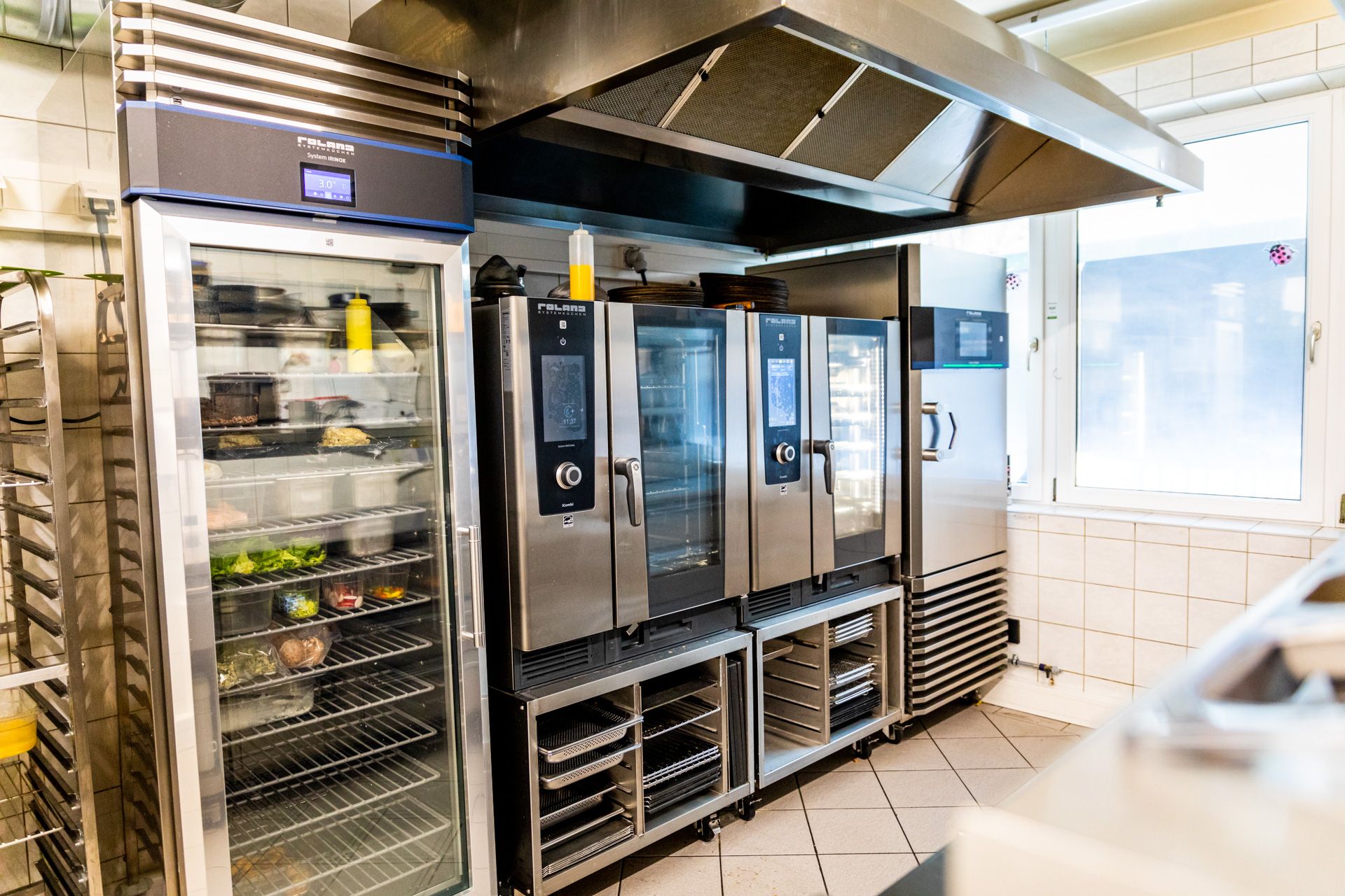 Moderne Systemküche mit Kombidämpfern, Kühlschrank und Edelstahl-Arbeitsflächen